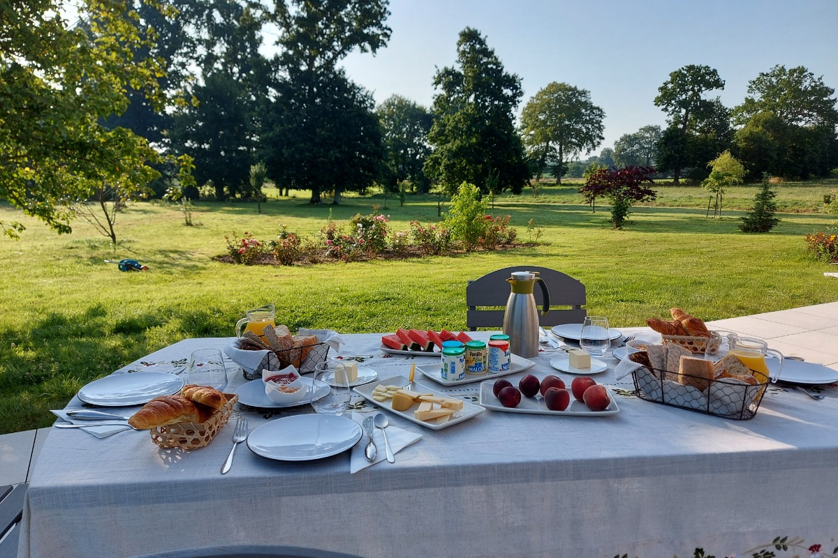 Table de petit déjeuner dressée dans le jardin à la belle saison. - Chambre d'hôtes - Combourg